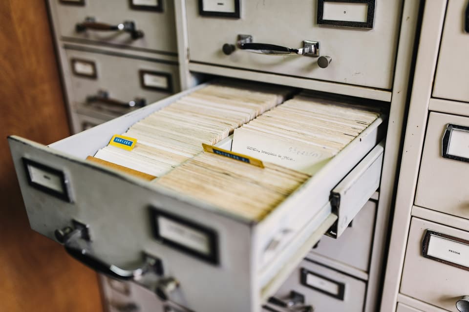 An open drawer of filed index cards in a cabinet