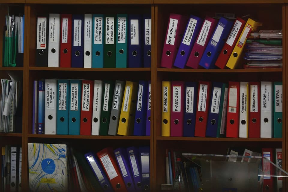 Binders and folders of documents on an office shelf